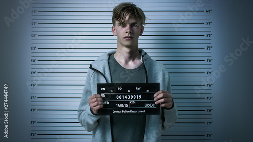 Photo In a Police Station Arrested Drug Addict Teenage Posing for a Front View Mugshot