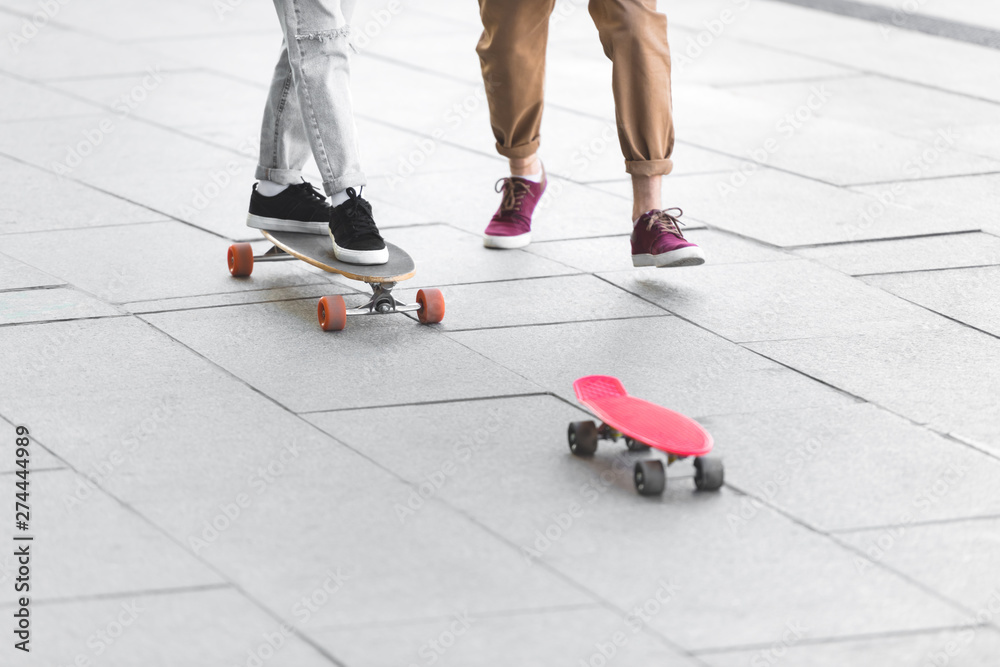 Fototapeta premium cropped view of man and woman riding on skateboards