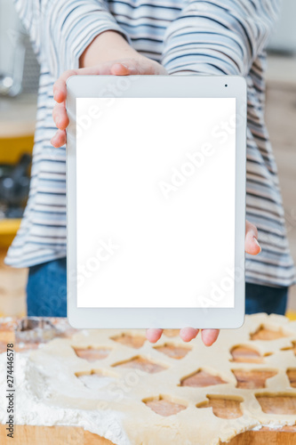 Online culinary course. Closeup of white mockup tablet screen. Woman holding device over rolled dough on the table.