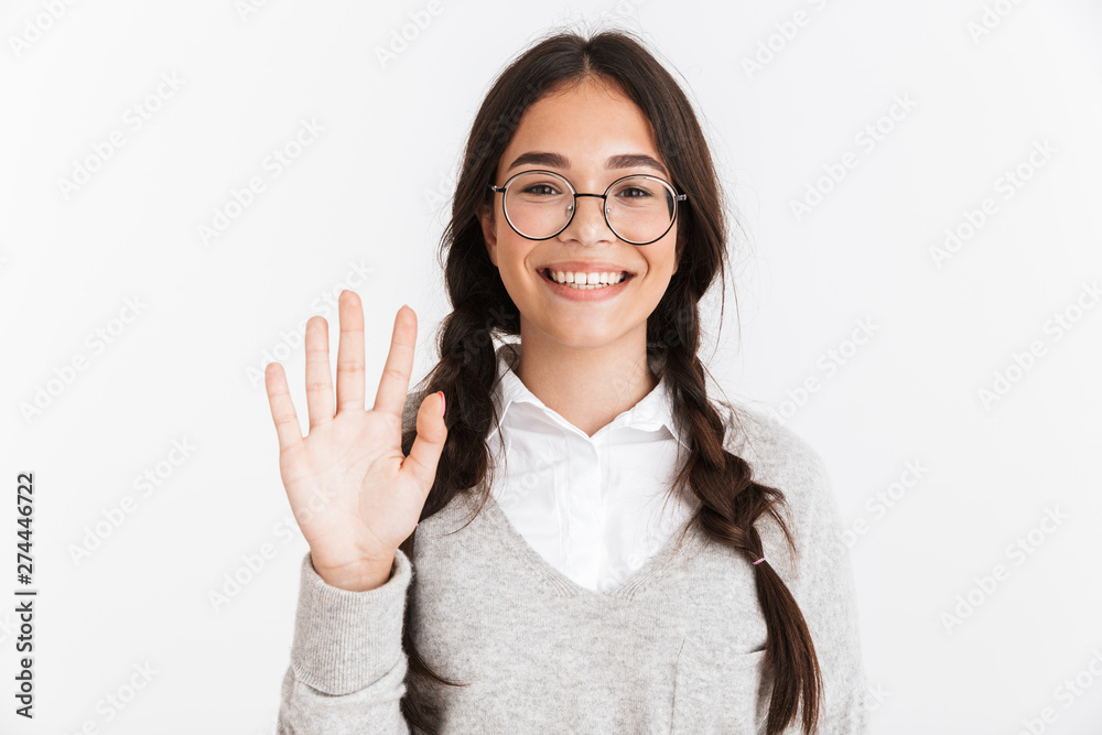 Photo closeup of cheerful teenage girl wearing eyeglasses and school uniform smiling while waving hand at camera Photo closeup of cheerful teenage girl wearing eyeglasses and school uniform smiling while waving hand at camera