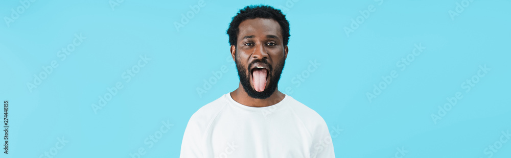 african american man sticking tongue out isolated on blue