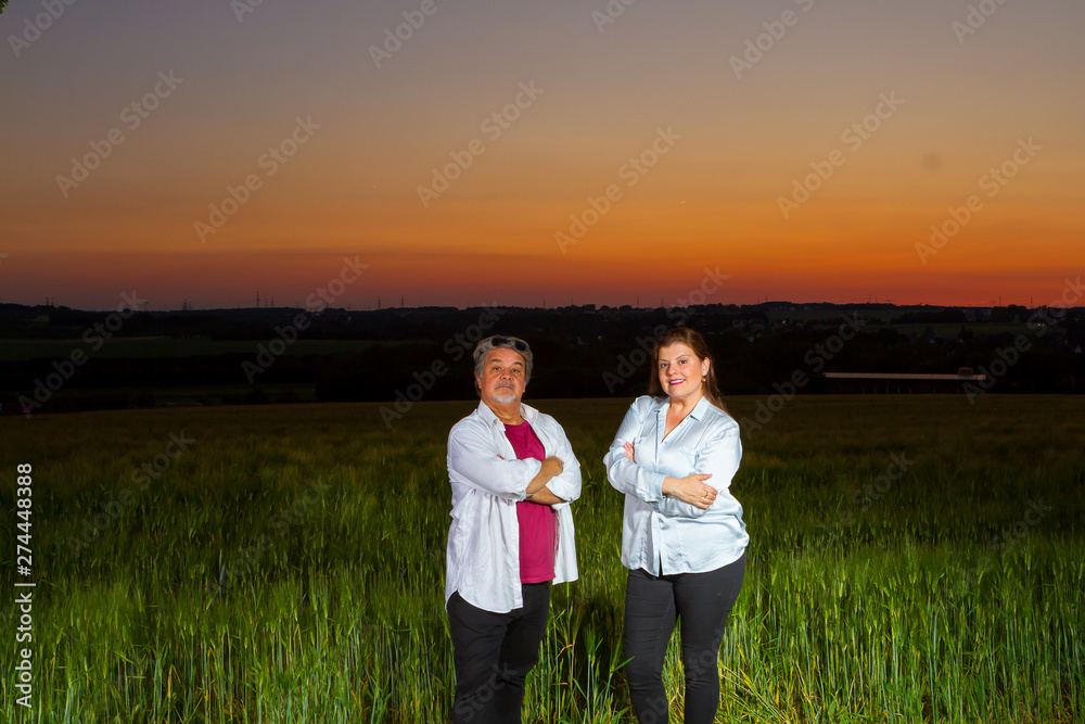 Man and woman poses standing together in an open field at end of the day out in the field with the beautiful landscape that nature presents with the sunset. Man and woman poses standing together in an open field at end of the day out in the field with the beautiful landscape that nature presents with the sunset.