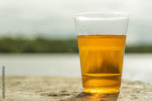 Plastic beer glass on concrete. On the background of the riverю Close up. Copy space