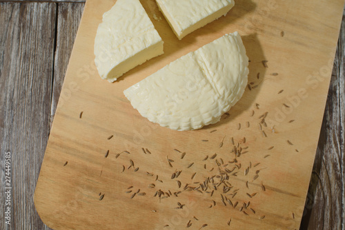 Fresh Adyghe cheese on a wooden tray on a wooden background
