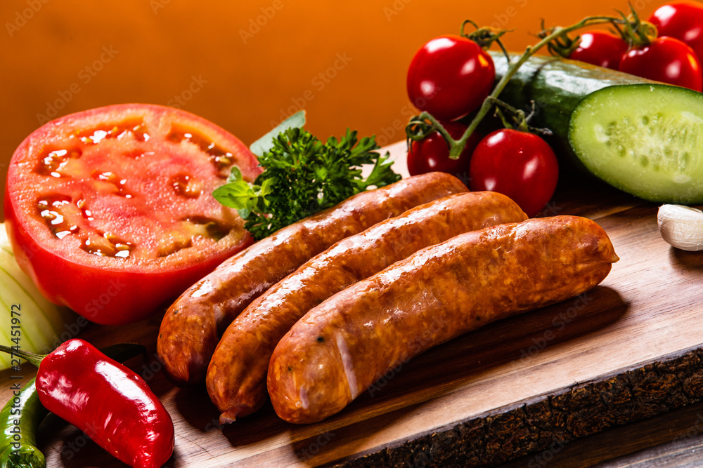 Raw sausages and vegetables on cutting board Raw sausages and vegetables on cutting board