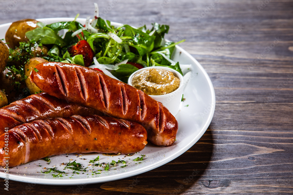 Grilled sausages, baked potatoes and vegetables