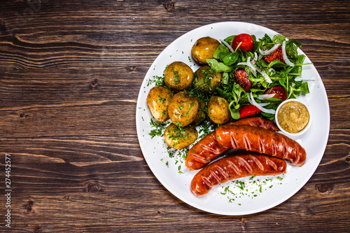 Grilled sausages, baked potatoes and vegetables