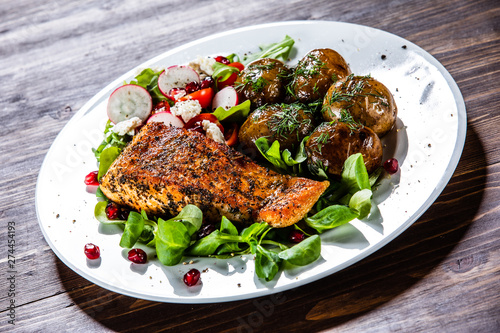 Grilled salmon, baked potatoes and vegetable salad