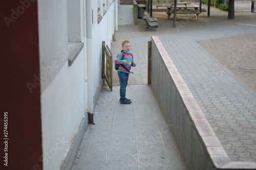 5 years old redheaded boy going to school looking back