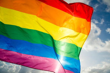 Close-up of gay pride rainbow flag fluttering backlit in bright sunny sky