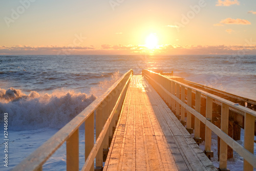 Yellow sun lights big storm waves. Sunset on the sea. Beautiful nature.