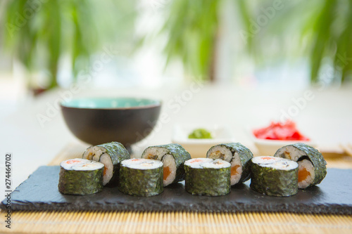 Sushi with salmon, avocado, rice in seaweed and chopsticks on wooden table. Japanese, Asian healthy food Healthy and tasty food. photo