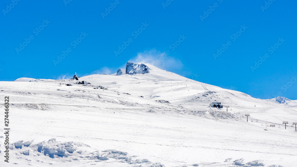 El pico Veleta de SIerra Nevada, Granada, nevado en un día soleado con el cielo azul.