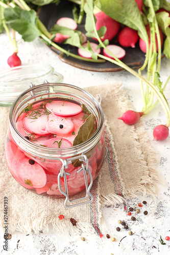 Pickled radish in a jar of herbs and garlic