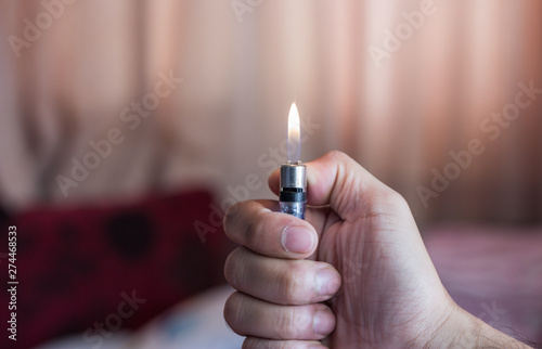 Wallpaper Mural Male hand lights a fire in the room under a muffled light. A large flame in the cigarette lighter on the background of the curtain. Torontodigital.ca