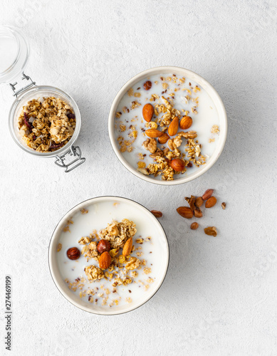 Granola breakfast with fruits, nuts, milk and peanut butter in bowl on a white background. Healthy breakfast cereal top view
