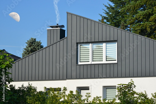 Fassaden- und Schornstein-Verkleidung eines modernen Wohngebäudes aus dunkelgrau beschichtetem Stehfalz-Metall und Fenster mit Sichtschutzstreifen,  photo