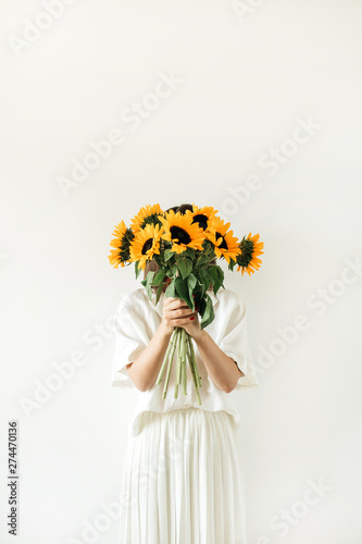 Young pretty woman in white dress hold sunflowers bouquet on white background. Florist minimal concept.