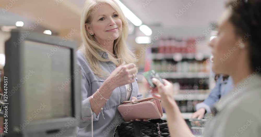Senior female paying for groceries in a food market