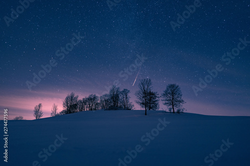 Hügel mit Sternenhimmel im Winter bei Schnee