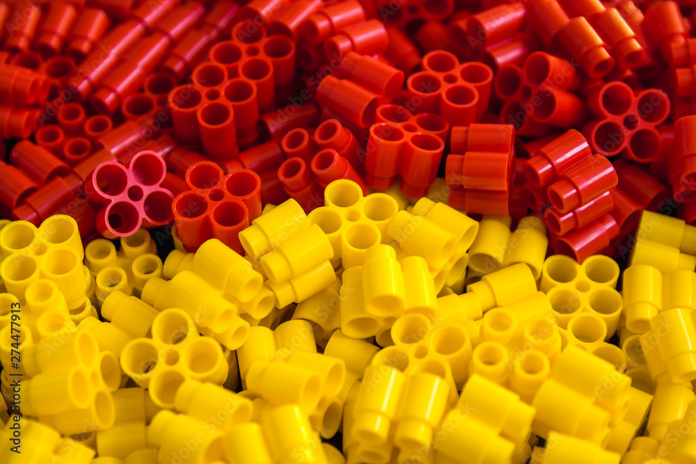 Obraz premium Plastic bricks of yellow and red on a background. Details of toys. Close up.
