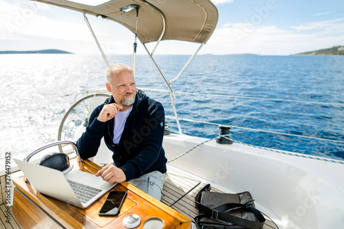Digitaler Nomade sitzt am Laptop auf einem Segelboot und blickt nach vorne