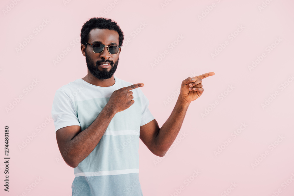 handsome african american of man in sunglasses pointing aside, isolated on pink handsome african american of man in sunglasses pointing aside, isolated on pink