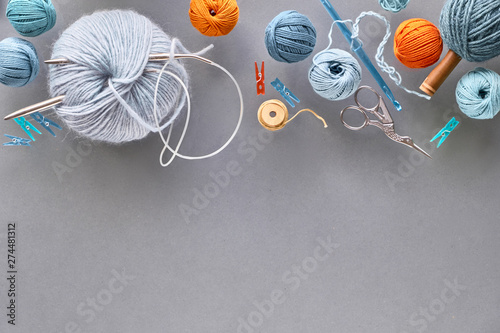Various wool yarn and knitting needles, creative knitting hobby background with text space