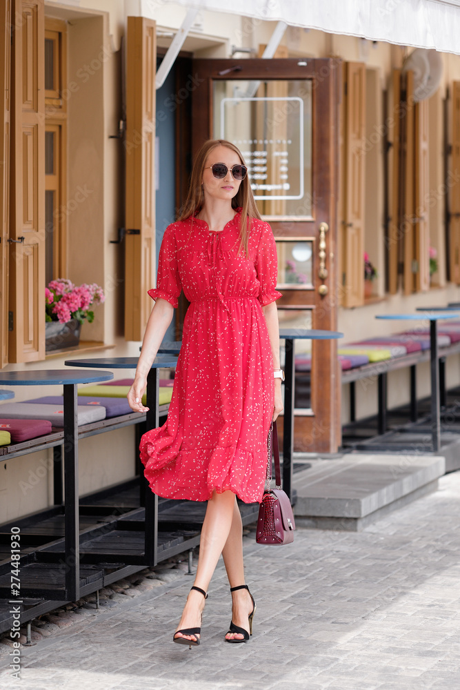 Pretty girl in red dress walking on the street in old town Pretty girl in red dress walking on the street in old town