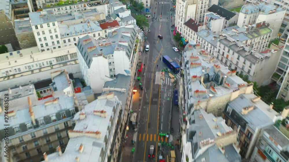 Aerial, tilt up, drone shot, over traffic on a french street, surrounded by buildings and architecture, in the city of Paris, on a sunny, summer day, in France