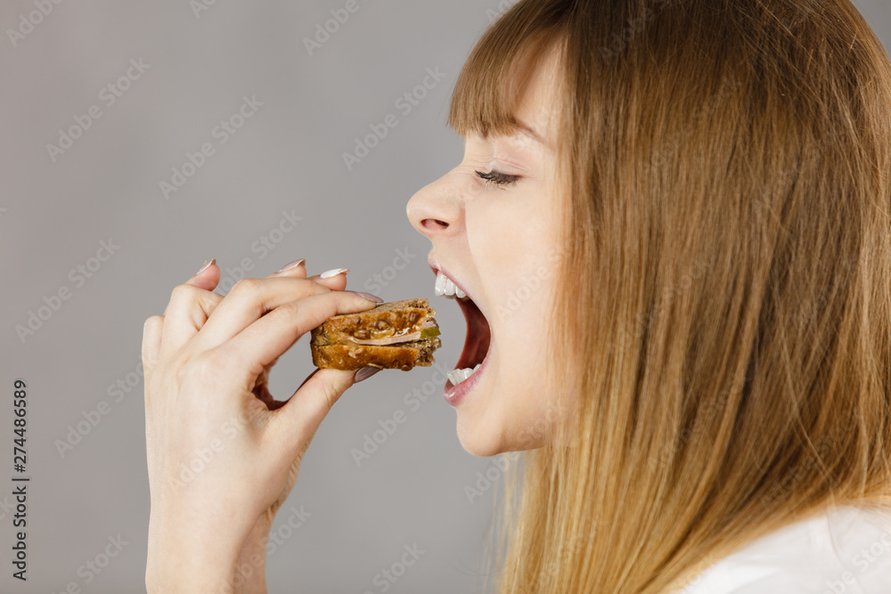 Woman eating sandwich, taking bite Woman eating sandwich, taking bite