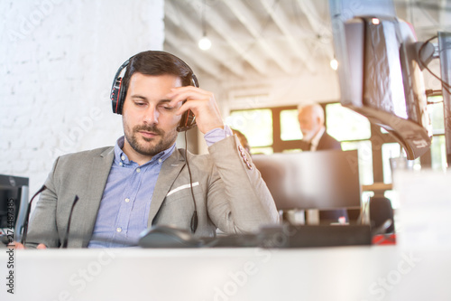 Tired call center operator having a headache in office