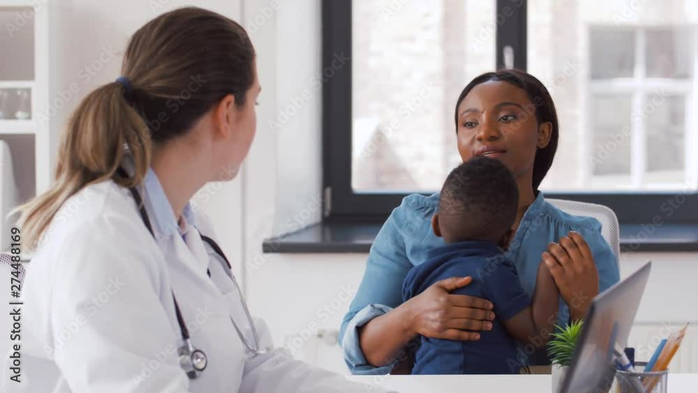 medicine, healthcare and pediatry concept - african american mother with baby son and caucasian doctor with laptop computer at clinic medicine, healthcare and pediatry concept - african american mother with baby son and caucasian doctor with laptop computer at clinic