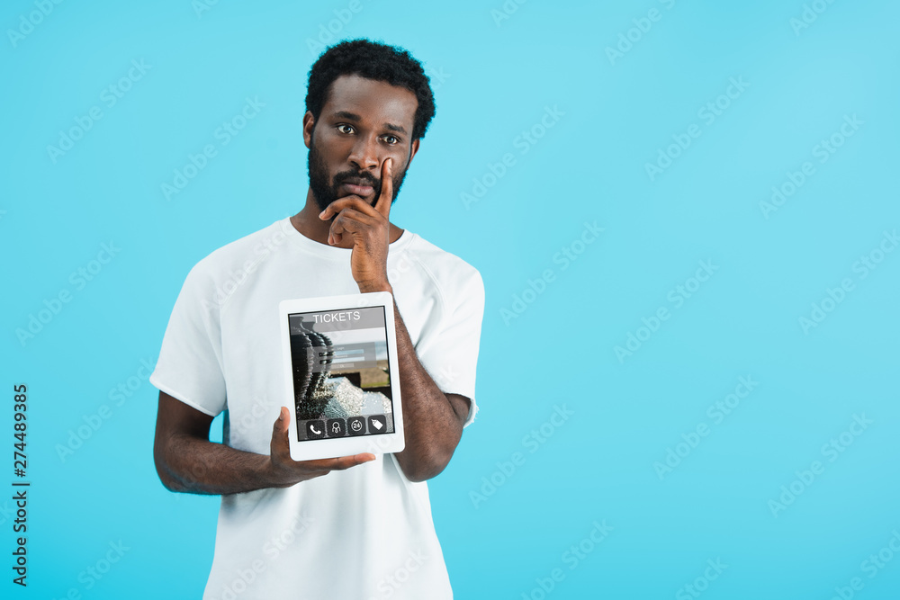 thoughtful african american man showing digital tablet with tickets app, isolated on blue thoughtful african american man showing digital tablet with tickets app, isolated on blue