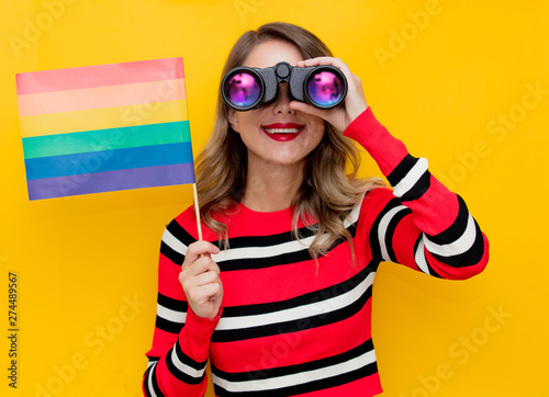 Young woman in red striped sweater with binocular and LGBT flag