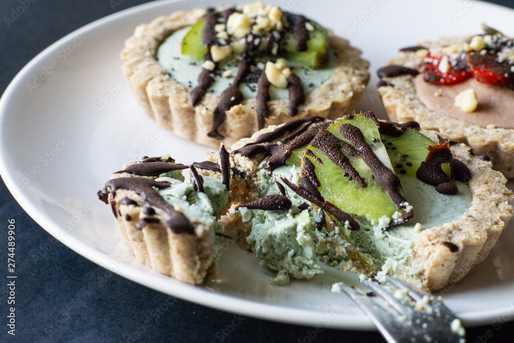 Raw vegan tartlets on the white plate. Healthy desserts, close up Raw vegan tartlets on the white plate. Healthy desserts, close up