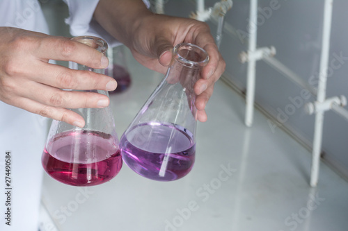in the hands of the laboratory assistant are flasks with a substance of red and purple. Flasks with reagents.