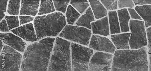 High resolution full frame background of a wall made of old and weathered stone slates in black and white. Copy space.