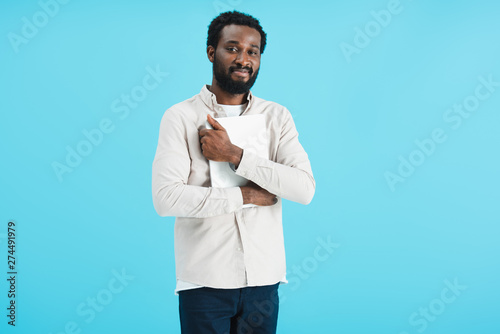 happy african american man holding laptop isolated on blue