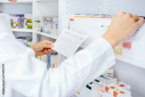 Medical pharmacists searching for medication by prescription in drugstore