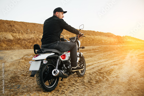Fototapeta Naklejka Na Ścianę i Meble -  Smiling happy biker in sitting on motorcycle on road