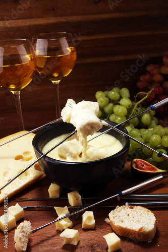 Gourmet Swiss fondue dinner on a winter evening with assorted cheeses on a board alongside a heated pot of cheese fondue