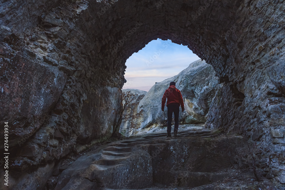 Man figure going through the stone arch in sunrise