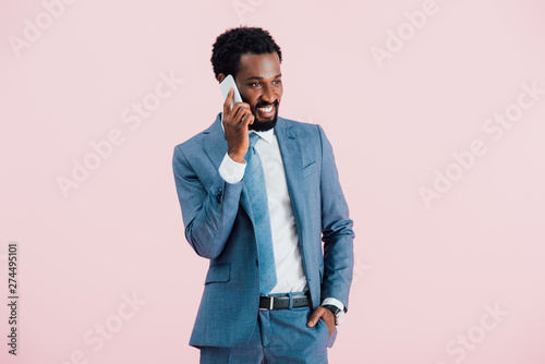 handsome african american businessman talking on smartphone, isolated on pink