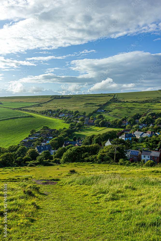 A view of a rural village (West Lulworth) from the hill under a majestic blue sky and some white clouds