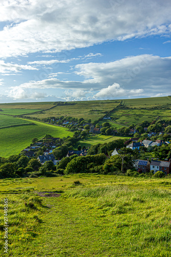 A view of a rural village  West Lulworth  from the hill under a majestic blue sky and some white clouds