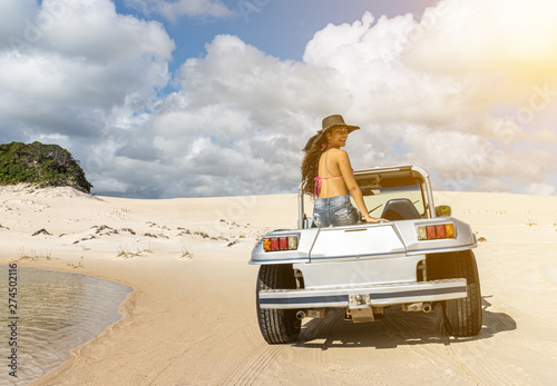 Canvastavla Beautiful happy young woman with buggy ride through the dunes of the coast of Brazil