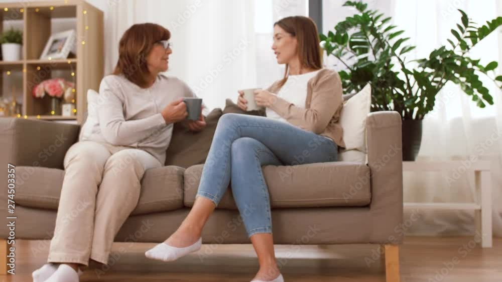 family, three generations and communication concept - mother and grandmother drinking coffee and daughter doing homework family, three generations and communication concept - mother and grandmother drinking coffee and daughter doing homework