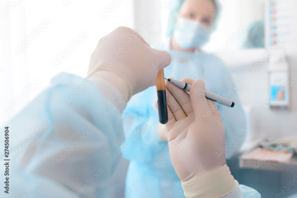 Blood in the test tube in the hands of man. The doctor holds a test tube with blood. Virus vaccine production. Coronavirus (COVID-19). Blood in the test tube in the hands of man. The doctor holds a test tube with blood. Virus vaccine production. Coronavirus (COVID-19).