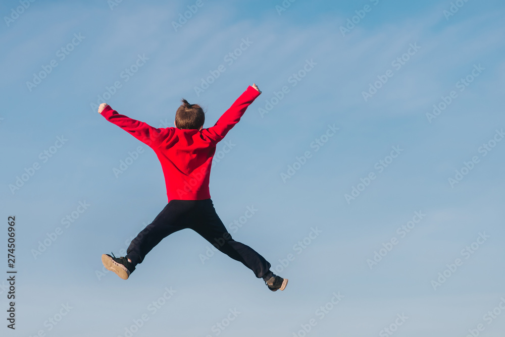 Happy boy is standing and looking into the distance. A child against the blue sky. Happy boy is standing and looking into the distance. A child against the blue sky.